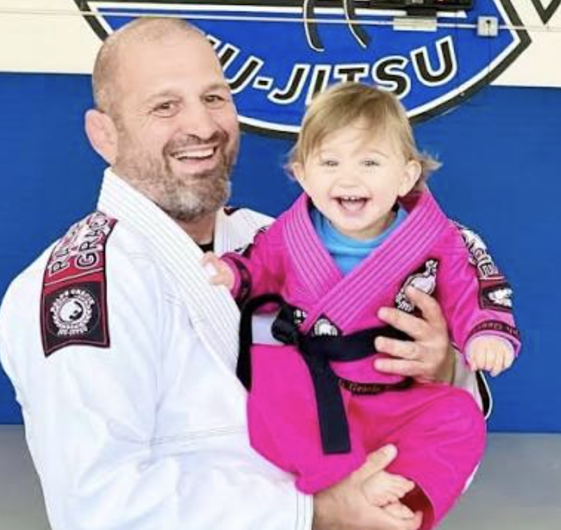Ralph segurando uma criança sorridente de kimono rosa